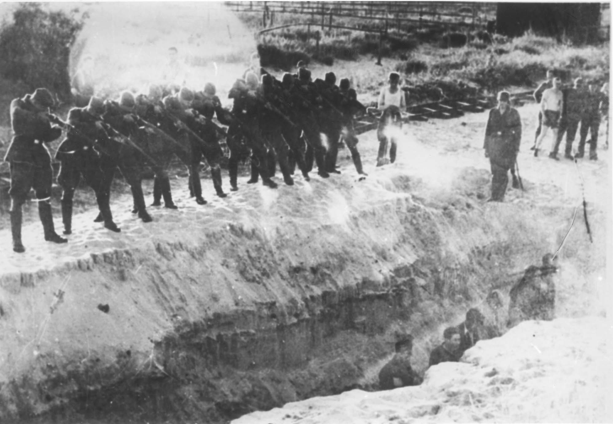 Einsatzgruppen soldiers shooting Jews who are in a ditch